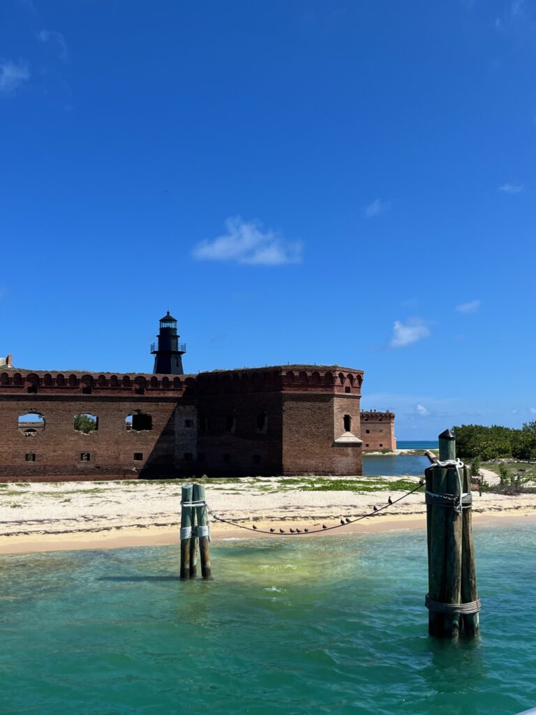 A sandy beach with one brick wall of Fort Jefferson. Fort Jefferson is located in Dry Tortugas National Park. 