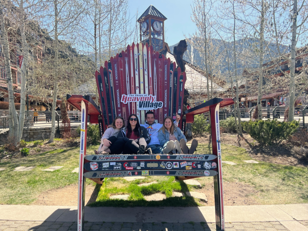 Madi (author), her two cousins, and sister sitting on an oversized chair made of skis in Heavenly Village.