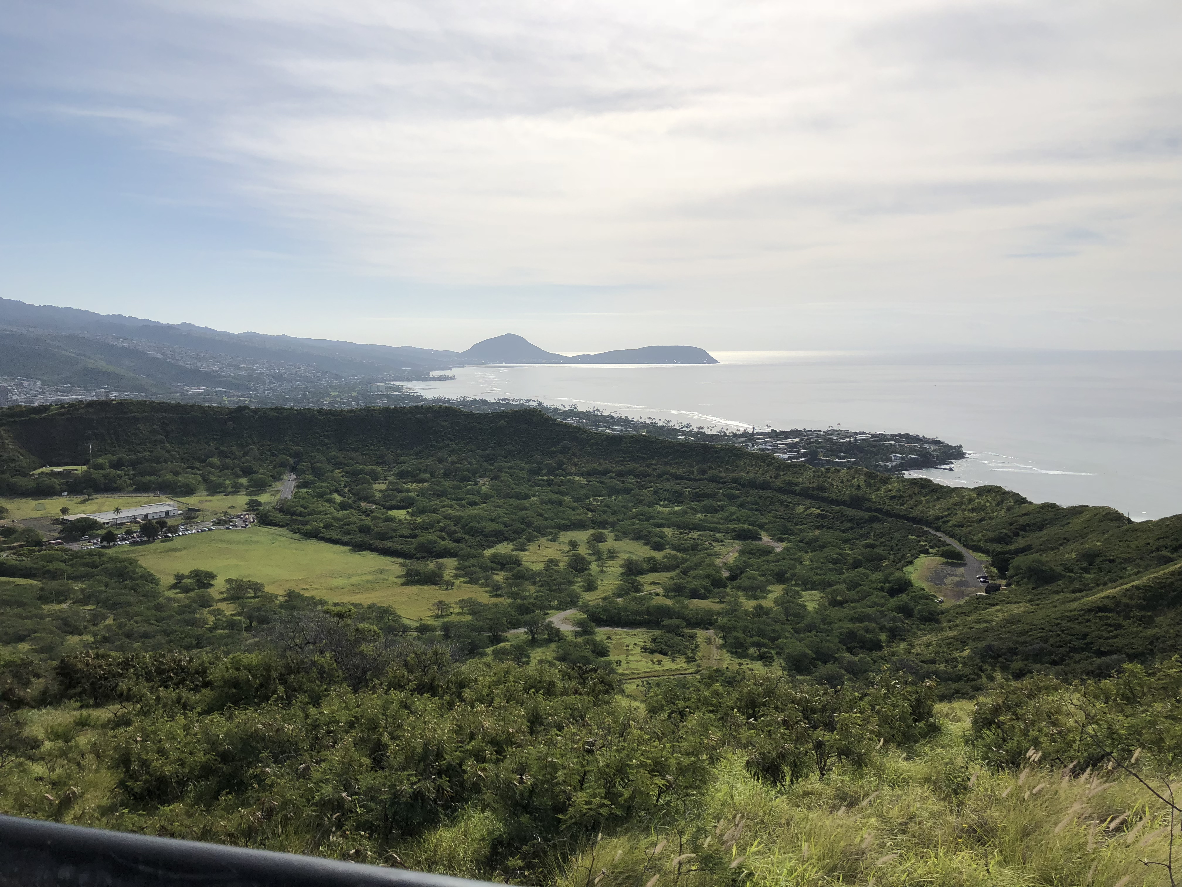 This photo shows the Diamond Head Crater, a very green crater in the Oahu landscape. You can also see the coastline and ocean in the background.