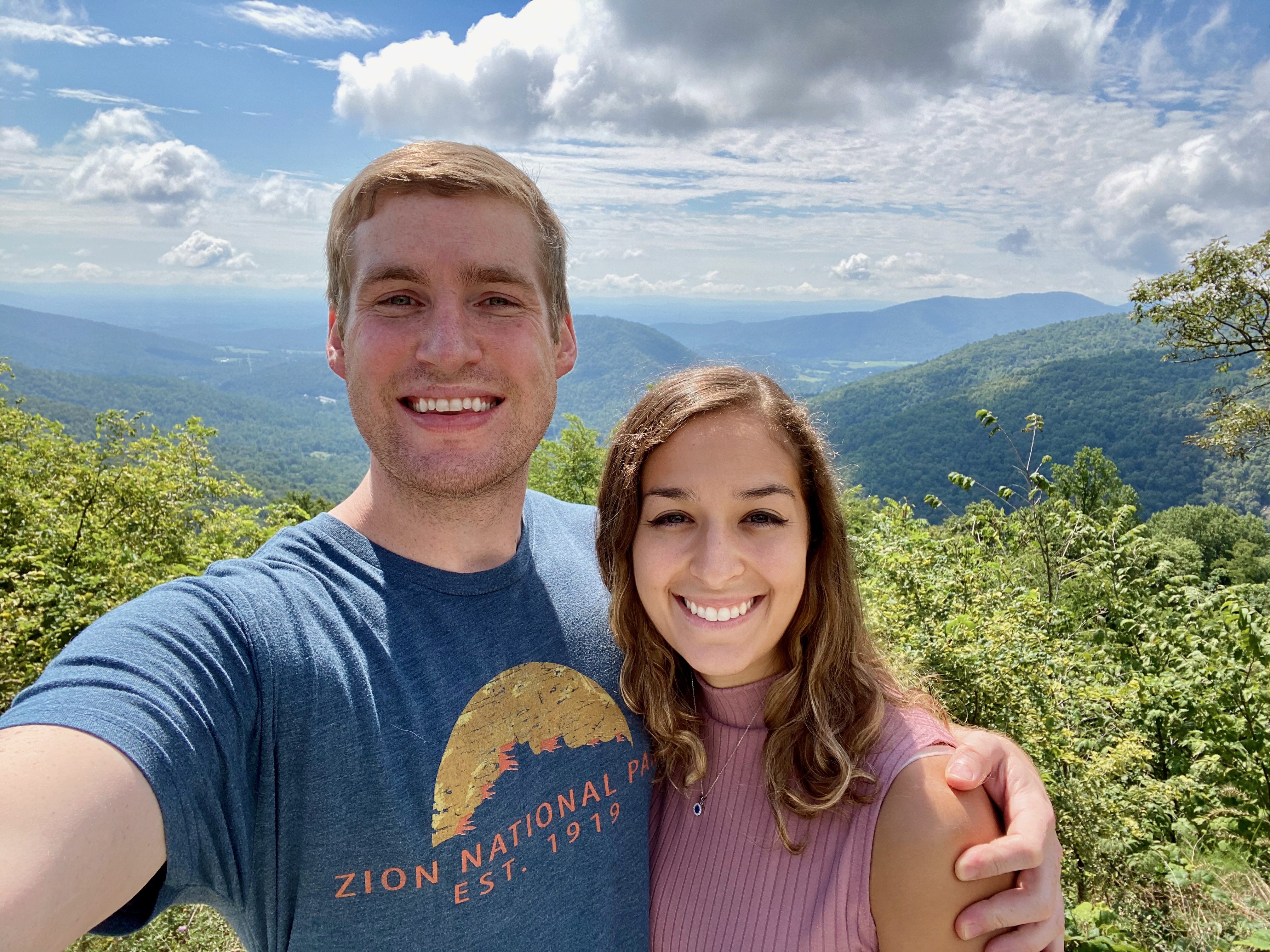 Couple standing at an overlook on Skyline Drive in Shenandoah, enjoying the breathtaking view of the Blue Ridge Mountains together, with a backdrop of scenic beauty and natural serenity.