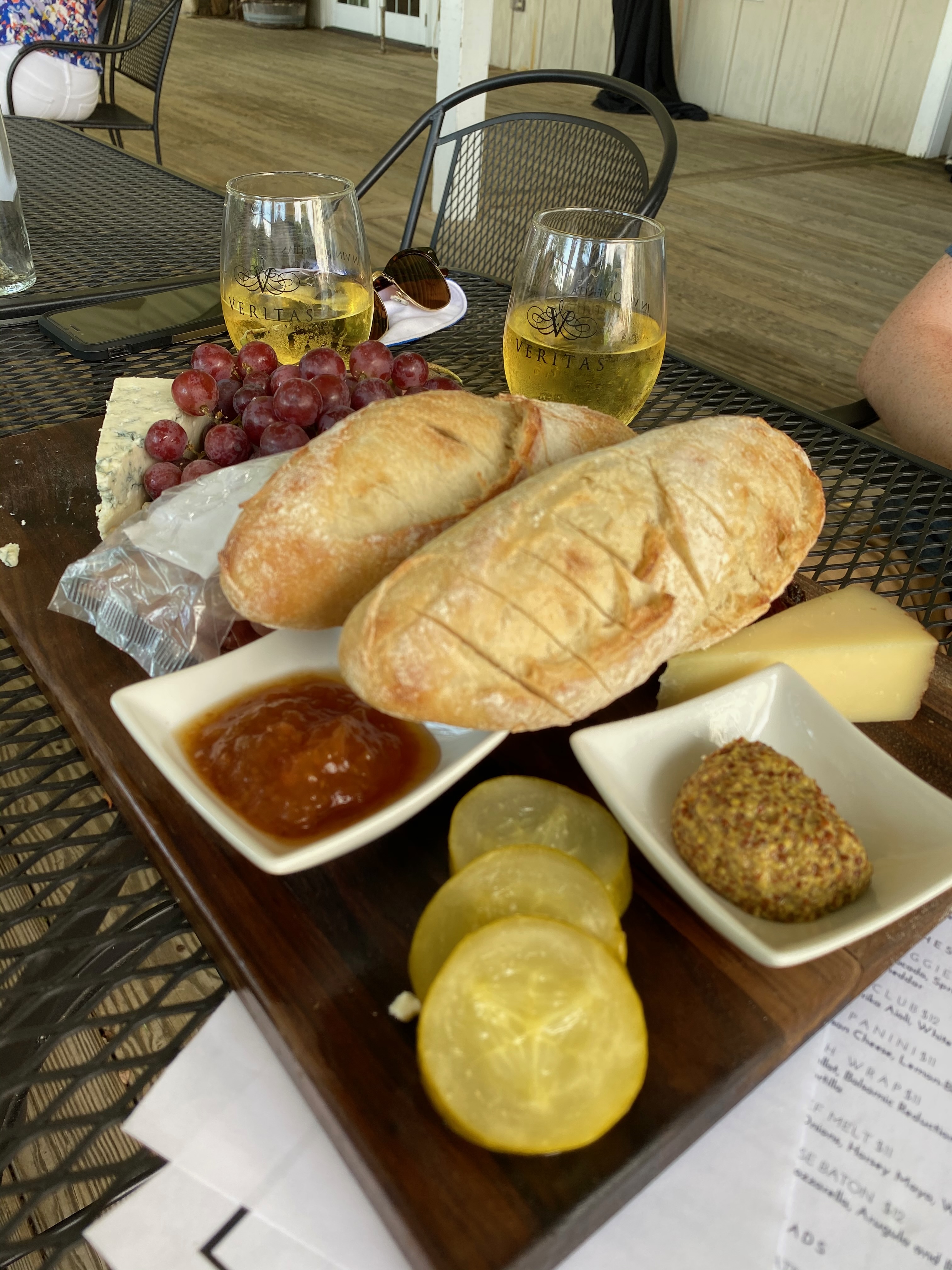 Artfully arranged charcuterie board with a delightful assortment of cheeses and accompaniments, paired with two glasses of white wine from Veritas Vineyard & Winery, creating a perfect setting for a sophisticated and enjoyable tasting experience.