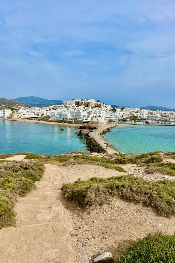 View of Chora town in Naxos with all the whitewashed buildings in the background with the light blue aegean sea surround it.