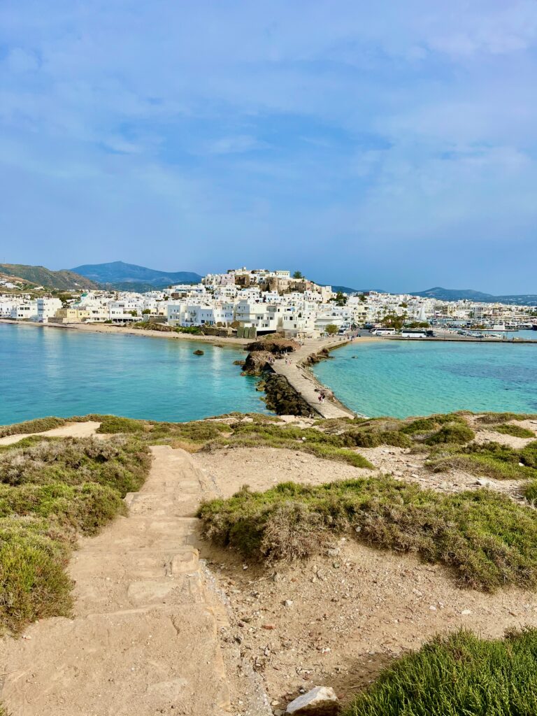 View of Chora town in Naxos with all the whitewashed buildings in the background with the light blue aegean sea surround it.