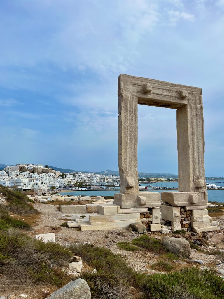 A breathtaking view capturing the majestic Temple of Apollo in the foreground, set against the backdrop of Naxos town. The ancient ruins stand in silent splendor, surrounded by the beauty of the landscape, while the charming white-washed buildings of Naxos town unfold in the distance, creating a harmonious blend of history and modernity. This historical landmark must be on your Naxos itinerary.