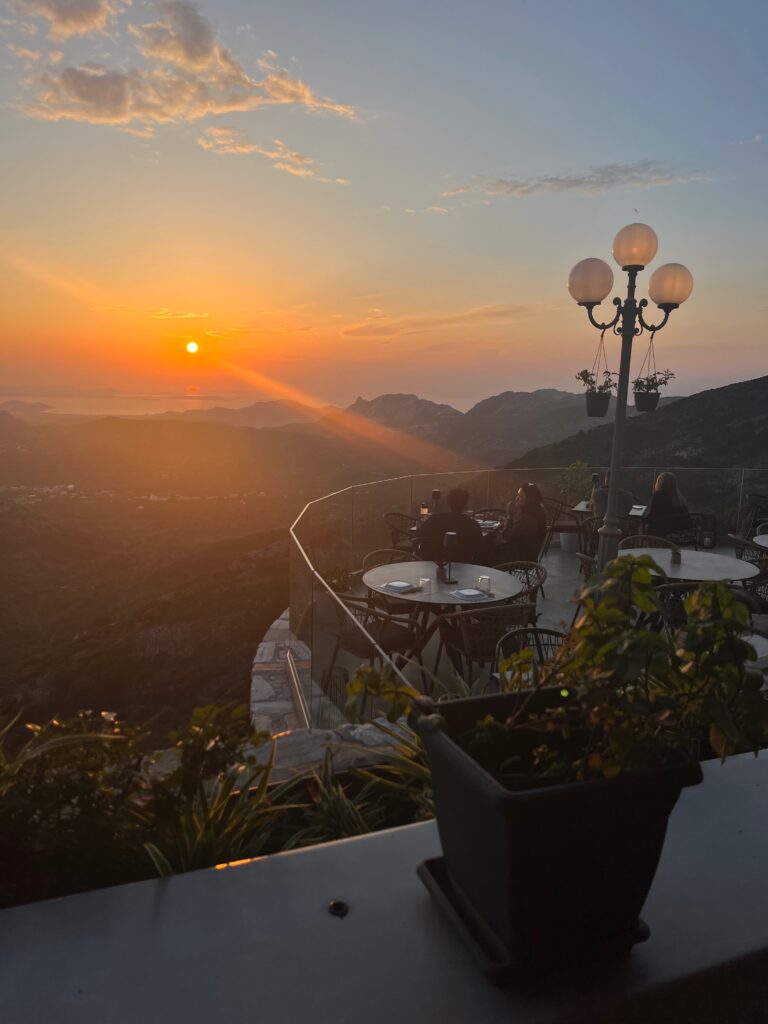 A captivating sunset dinner scene at the Rotunda restaurant in Naxos. Warm hues of the setting sun paint the sky, casting a golden glow on the outdoor dining area. Tables adorned with elegant settings overlook the tranquil surroundings, creating a perfect ambiance for a romantic and memorable evening in Naxos. This restaurant is another must on your Naxos Itinerary.