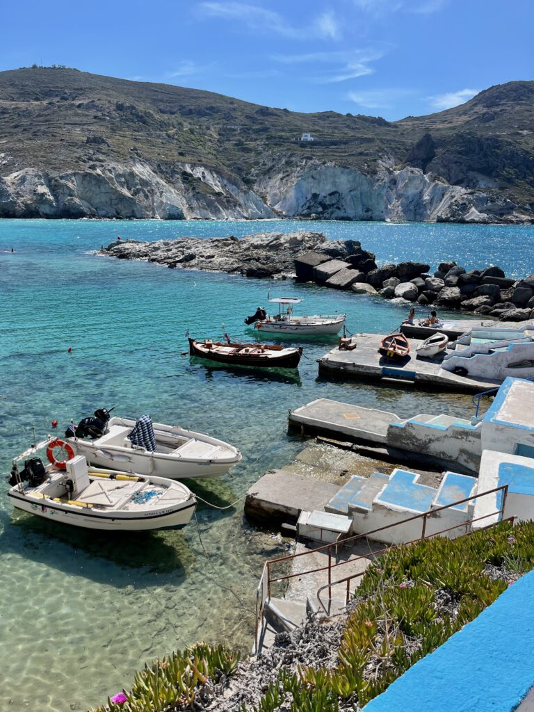 Charming view of the traditional fisherman village in Mandrakia, Milos, Greece, featuring colorful boat houses along the crystal-clear waters, embodying the rustic allure of coastal Greek life